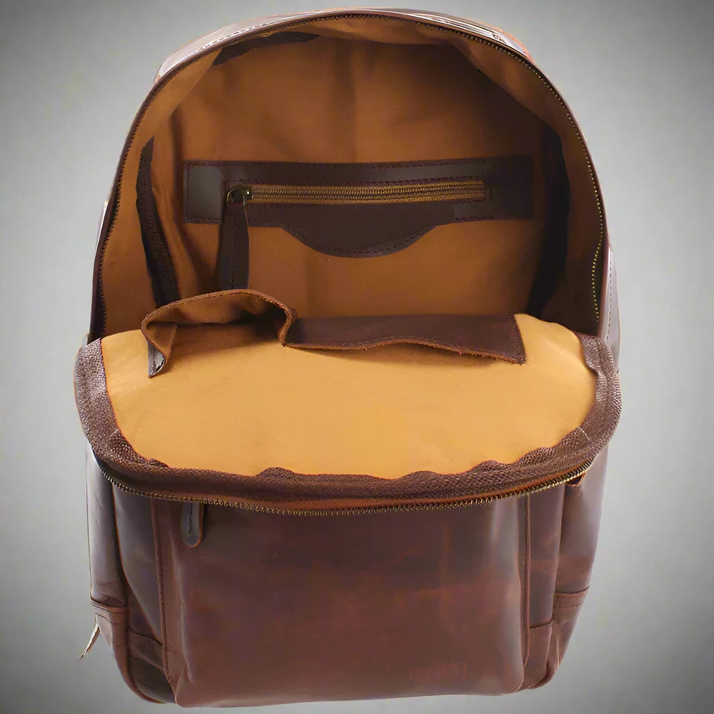 Open brown Atlas leather backpack showing fabric lining, interior zip pocket, and slip compartments