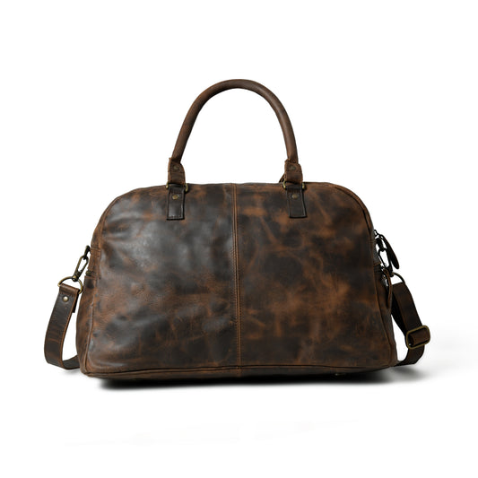 Waxed Cow Leather weekender duffel, close product view showing stitching and material texture. A dark brown distressed leather duffel bag with top handles and a detachable shoulder strap, shown against a plain white background.