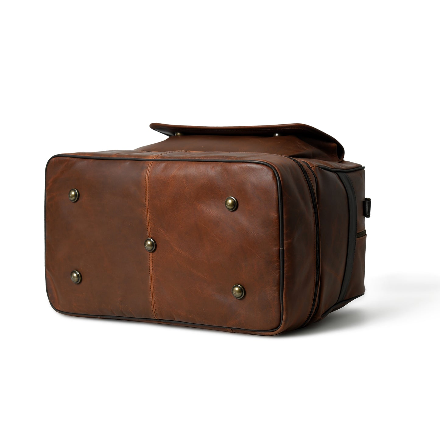 A brown leather travel or luggage bag with brass snap buttons on the bottom, shown from a three-quarters angle on a white background.