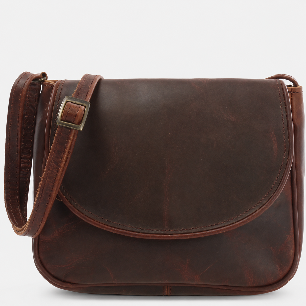 A dark brown Cuiravo Elara suede leather crossbody bag with a curved front flap, a matching leather shoulder strap with a brass buckle, and a clean white background.